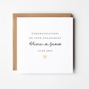 May include: Square engagement card with a brown envelope. The white card reads "Congratulations on Your Engagement" above the names "Olivia & James" and the date "14.02.2025". A small gold heart is at the bottom.