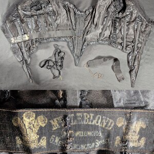 May include: A vintage black corset with boning, seams, and a label. The corset has a structured design with multiple panels and a front closure. The label features gold text and a crest. Additional black ribbons and straps are included.