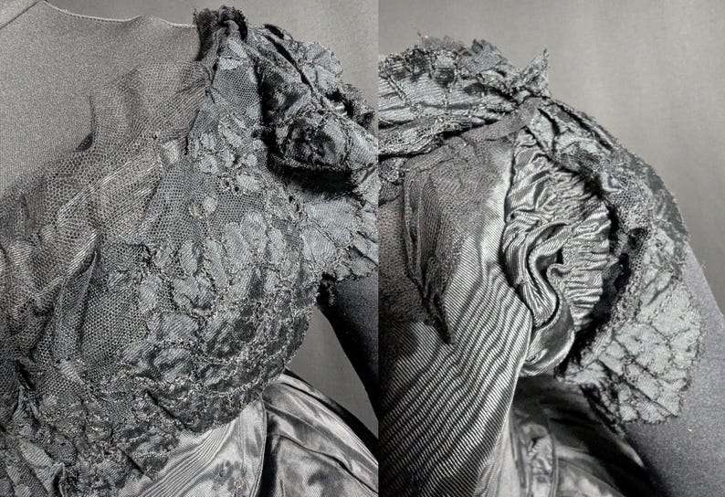 May include: Close-up of a black vintage dress bodice. The dress features intricate lace detailing on the sleeves and bodice, with a textured, layered design. The fabric appears to be a combination of satin and lace, creating a rich, dark aesthetic.