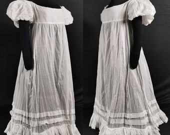 Puede incluir: Un vestido blanco de algodón con falda fruncida y mangas abullonadas. El vestido tiene un diseño simple y elegante y es perfecto para una variedad de ocasiones.
