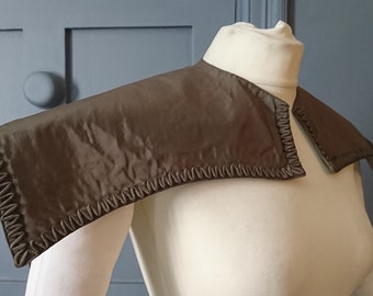 May include: A brown fabric collar with a ruffled edge. The collar is on a white mannequin.