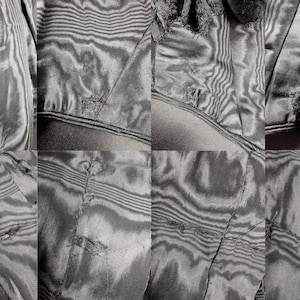 May include: Close-up of sections of a dark gray fabric with a subtle, wavy pattern. The fabric appears to be damaged, with visible tears and frayed edges. The image is a detailed study of the textile's texture and condition.