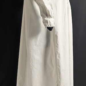 May include: A long, white nightgown with a high neckline and long sleeves. The nightgown features delicate lace trim around the collar and cuffs. The fabric appears to be a lightweight cotton or linen.