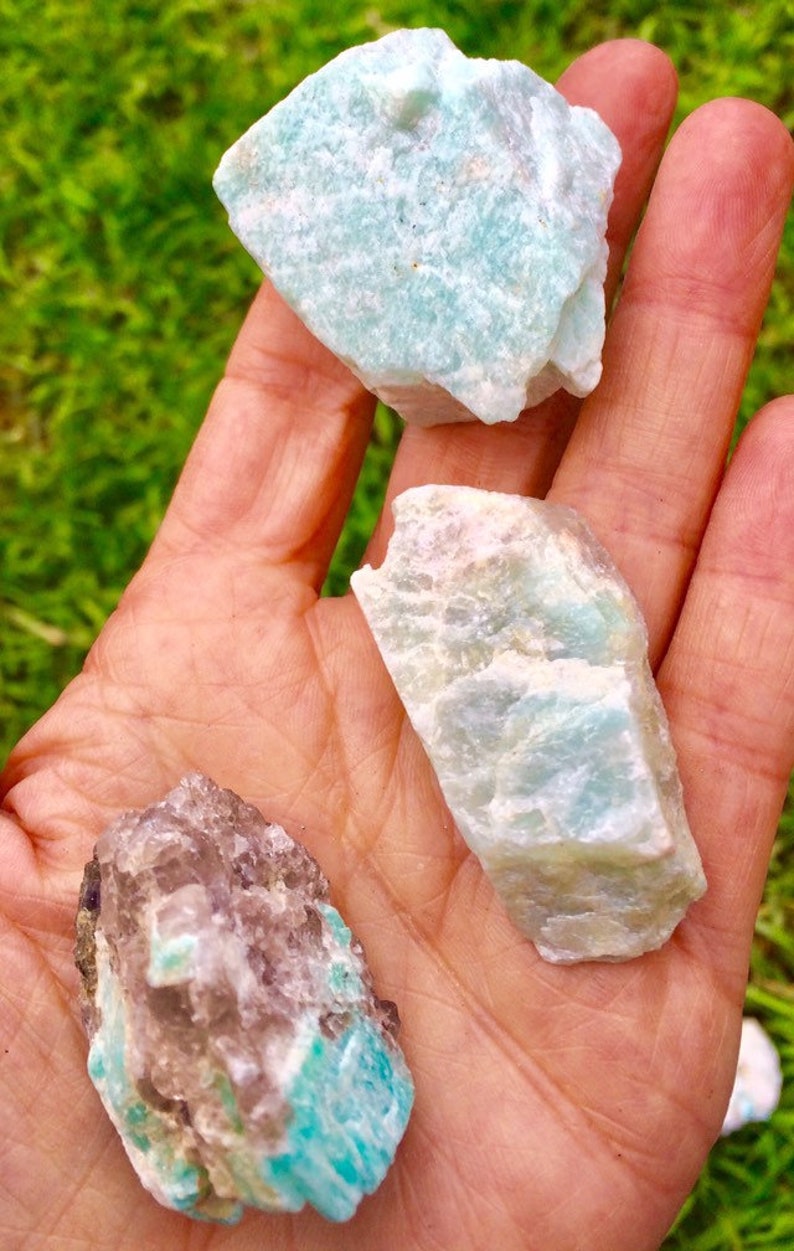 May include: Three rough, natural, green and white amazonite crystals. The crystals are various sizes and shapes.