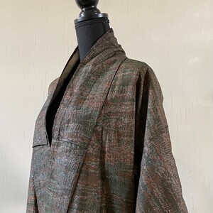 May include: A brown and green patterned kimono with a V-neck and long sleeves.