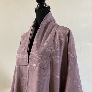 Pode incluir: Um quimono malva com um padrão floral. O quimono é feito de um tecido macio e sedoso e tem um design japonês tradicional.