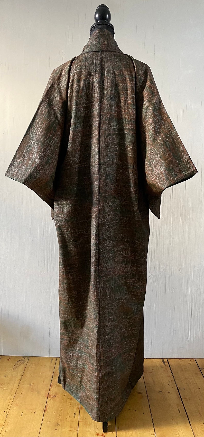 May include: A long, brown and green patterned kimono with a traditional Japanese design. The kimono is made of a soft, flowing fabric and has a relaxed fit.