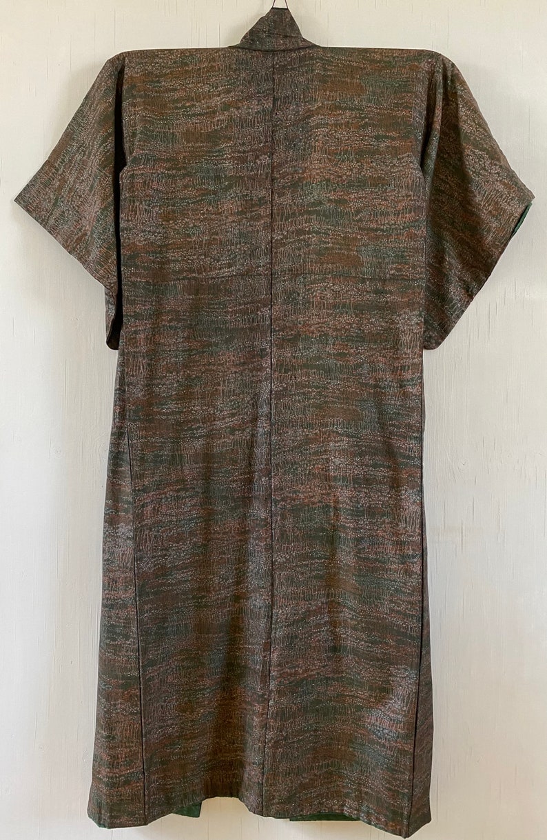 May include: A brown and green patterned kimono with short sleeves. The kimono is made of a silky fabric and has a subtle sheen.
