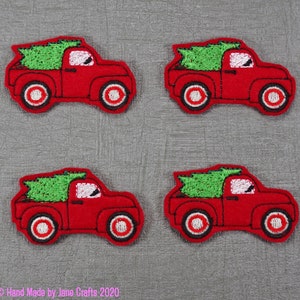 May include: Four red felt Christmas truck appliques with green felt Christmas trees in the back of the trucks. The trucks have white wheels with black outlines.