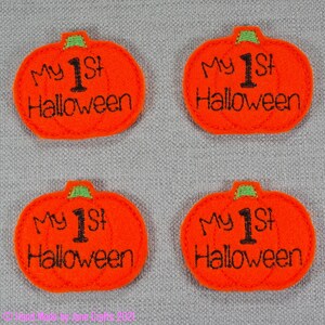 May include: Four orange felt pumpkin patches with green stems and the text "My 1st Halloween" in black embroidery.