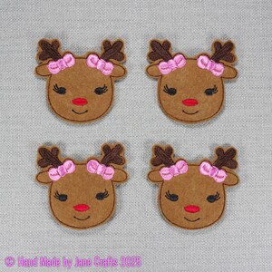 May include: Four brown felt reindeer heads with dark brown antlers and pink bows. Each reindeer has black eyelashes, a red nose, and a smiling red mouth. The text "Hand Made by Jane Crafts 2025" is in the bottom left corner.