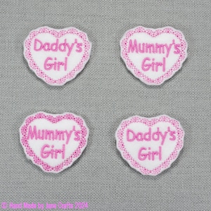 May include: Four pink and white heart-shaped embroidered patches with the text "Daddy's Girl" and "Mummy's Girl".