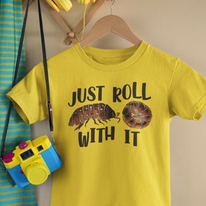 May include: Yellow t-shirt with the text "Just Roll With It" and a graphic of a brown pill bug and a brown and white pill bug.