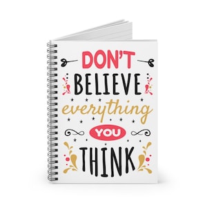 May include: A white spiral notebook with the text "DON'T BELIEVE everything YOU THINK" in black, pink, and gold lettering. The notebook has a white background with gold and pink floral designs.