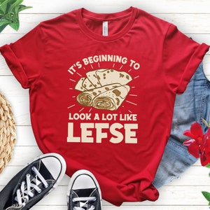May include: Red t-shirt with the text "It's beginning to look a lot like Lefse" and a graphic of three rolled lefse.