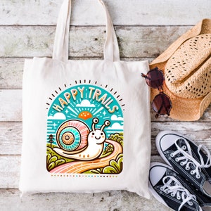 May include: A white canvas tote bag with a colorful illustration of a snail on a winding path. The illustration is surrounded by a circle with the text "Happy Trails" in a colorful font.