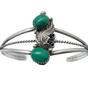 May include: A silver bracelet featuring two green malachite stones and a decorative silver design.