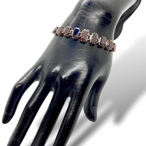 May include: A silver bracelet with a row of rectangular red and blue gemstones.
