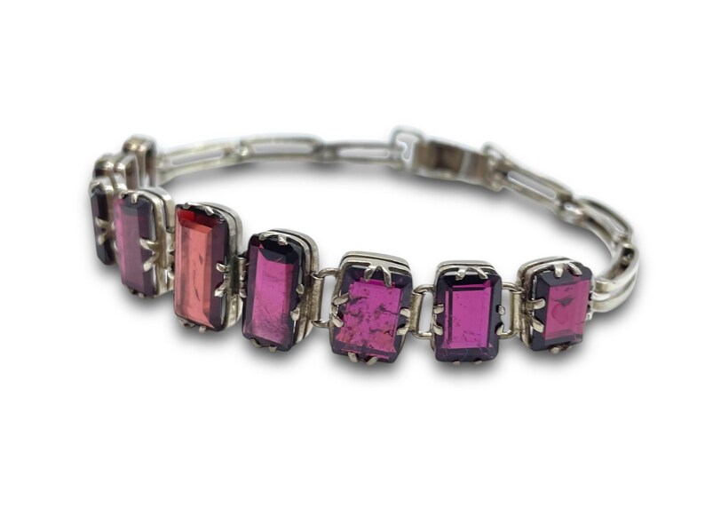 May include: A silver bracelet with a chain link design and rectangular pink and purple gemstones.