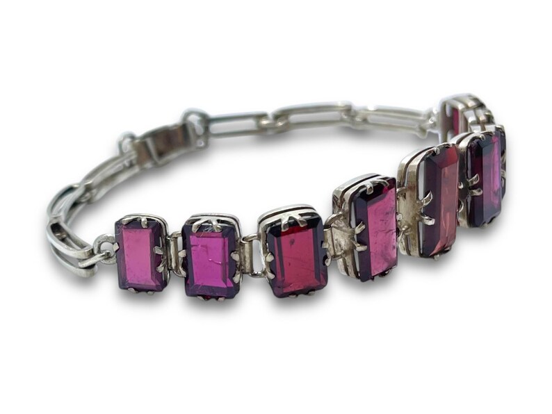 May include: A silver bracelet with a chain link design and rectangular purple gemstones.