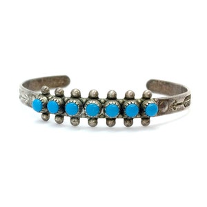 Puede incluir: Una pulsera de plata con piedras turquesa y un diseño de flecha.