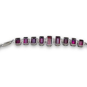 May include: A silver bracelet with a row of rectangular purple gemstones.
