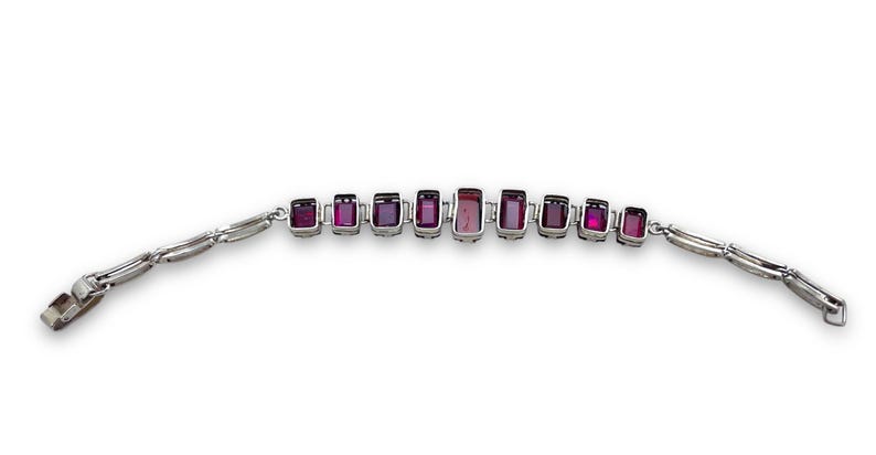May include: A silver bracelet with a row of rectangular purple gemstones.