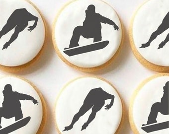 May include: Six round sugar cookies decorated with black silhouettes of snowboarders. The cookies are on a white surface.