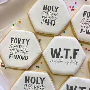 May include: Six hexagonal cookies decorated with black icing and funny sayings for a 40th birthday. The sayings include "Forty the Ultimate F-Word", "Holy #%@* You're 40", "W.T.F. who's turning forty", and "Fort the Ultima F-Wor".