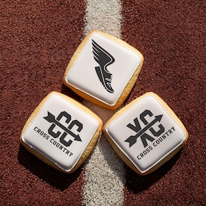 May include: Three square cookies decorated with cross country running themed designs. One cookie features a running shoe with wings, another has the letters "CC" with an arrow, and the third has the letters "XC" with an arrow. All cookies have the text "Cross Country" printed on them.