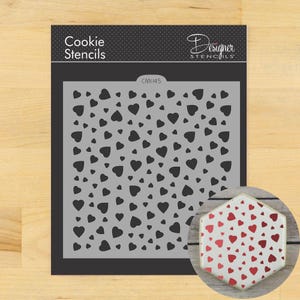 May include: A gray cookie stencil with a pattern of black hearts. The stencil is labeled "Cookie Stencils" and "Designer Stencils." A decorated cookie with a red heart pattern is shown in the lower right corner.