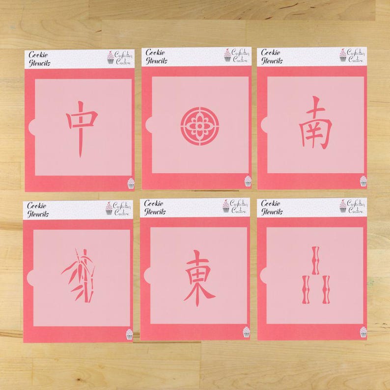 May include: Six pink cookie stencils with Chinese characters and symbols. The stencils are arranged in two rows of three. The stencils are made of plastic and are reusable.