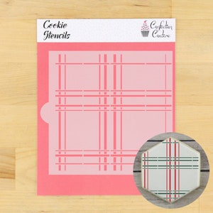 Może przedstawiać: Różowa szablon do ciasteczek z wzorem w kratkę. Szablon jest przeznaczony do użycia z lukrem lub lukrem królewskim, aby stworzyć wzór w kratkę na ciasteczkach. Szablon jest pokazany z ozdobionym ciasteczkiem w prawym dolnym rogu.