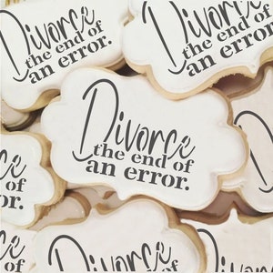 May include: A close-up of several white cookies decorated with black icing. The cookies have the text "Divorce the end of an error." on them.