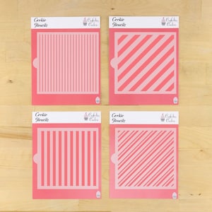 Puede incluir: Cuatro plantillas para galletas de color rosa, dos con rayas verticales y dos con rayas diagonales. Las plantillas están etiquetadas como "Cookie Stencils" y "Confection Couture".