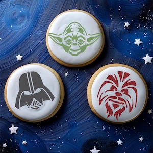 Op de afbeelding: Drie ronde suikerkoekjes versierd met glazuur en sjablonen van Star Wars-personages. De koekjes tonen Darth Vader, Yoda en Chewbacca.