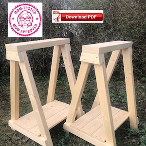 May include: Two wooden sawhorses, made of unfinished pine wood, are standing on a grassy surface. The sawhorses are identical in design and construction.  The sawhorses are approximately 76 cm tall and 61 cm wide.  The sawhorses are designed to be used as a work surface for projects.