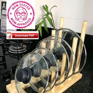 May include: A wooden lid holder with five glass lids stacked on top of each other. The holder is made of natural wood and has a rustic look.