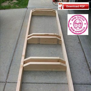 Puede incluir: Un portabicicletas de madera con cuatro ranuras para guardar bicicletas. El portabicicletas está hecho de madera sin terminar y está ensamblado sobre una superficie de concreto.