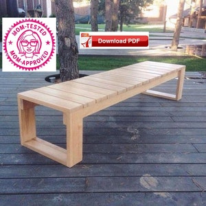 May include: A wooden bench with a slatted top and a simple rectangular frame. The bench is made of light-coloured wood and is sitting on a wooden deck.
