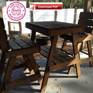 Könnte beinhalten: Ein Holztisch und zwei Stühle auf einer Betonterrasse. Tisch und Stühle sind aus unbehandeltem Holz und haben einen rustikalen Look. Der Tisch hat eine quadratische Tischplatte und die Stühle haben ein schlichtes Design.
