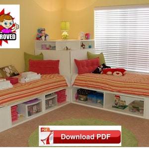 Op de afbeelding: Een wit hoekbedframe met ingebouwde opbergplanken. Het bed is gemaakt met een rood-geel gestreept beddengoed en heeft twee rode kussens. Het bed staat in een kamer met gele muren en een witte jaloezie.