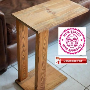 Op de afbeelding: Een houten bijzettafel met een rustieke afwerking. De tafel heeft een rechthoekig blad en een enkel been aan elke kant. De tafel staat op een betegelde vloer. De afbeelding bevat ook een roze en witte stempel met de tekst "Mom-Tested Mom-Approved" en een rood PDF-pictogram met de tekst "Download PDF".