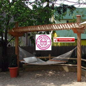 Może przedstawiać: Drewniana pergola z hamakiem wiszącym pod spodem. Pergola wykonana jest z naturalnego drewna i ma dach z listew. Hamak jest biały i ma białą poduszkę. Pergola znajduje się na podwórku z ogrodzeniem i zielonymi roślinami w tle. Na zdjęciu znajduje się również czerwona doniczka z zieloną rośliną i czerwono-biała naklejka "Testowane przez mamę, zatwierdzone przez mamę".