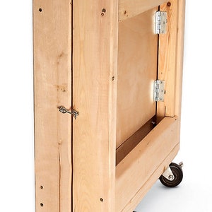 May include: A wooden folding table with wheels. The table is made of natural wood and has a simple design. It is folded up and ready to be moved.