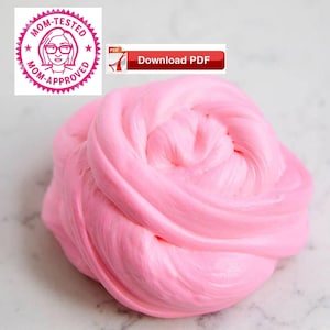 Könnte beinhalten: Nahaufnahme einer rosa Schleim, ein beliebtes Kinderspielzeug, mit einer weichen, flauschigen Textur. Der Schleim ist in einer großen, runden Form und scheint sehr dehnbar zu sein.