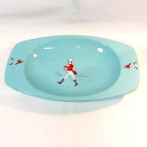 Op de afbeelding: Een lichtblauwe asbak van keramiek met een afbeelding van een lopende man en de tekst "Born 1820 - Still Going Strong".