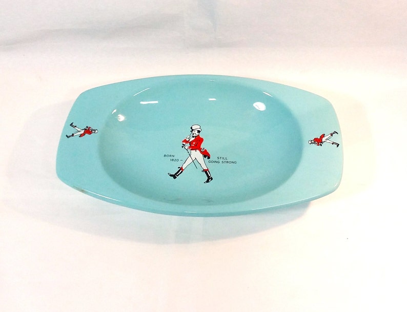 May include: A light blue ceramic ashtray with a walking man graphic and the text "Born 1820 - Still Going Strong".