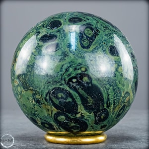 May include: A green gemstone sphere with dark green and black markings, displayed on a gold-coloured base. The polished orb has a glossy surface. This decorative item is a unique home decor piece.