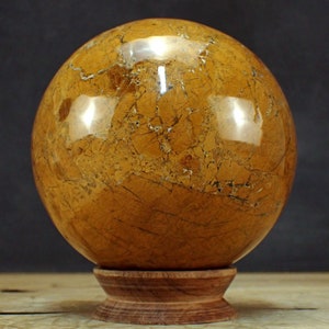 Peut inclure: Une sphère d'agate polie de couleur brun doré avec un motif marbré, reposant sur un support en bois.
